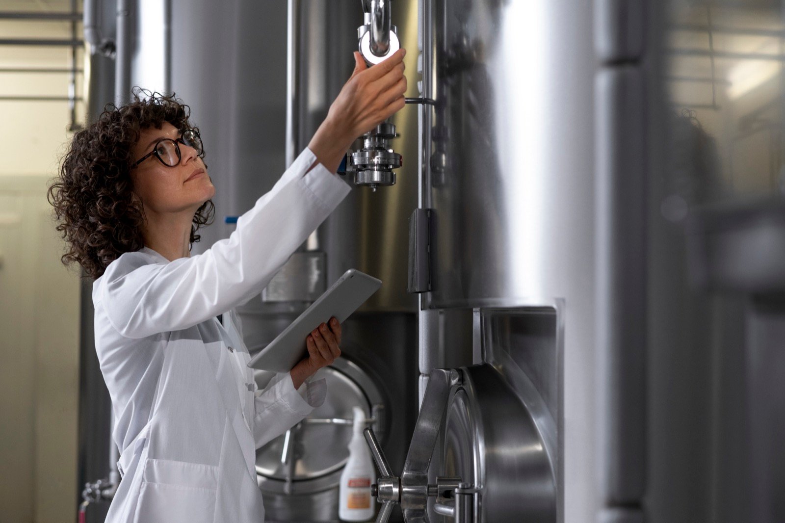 Técnica revisando tanques de acero inoxidable en una planta de producción